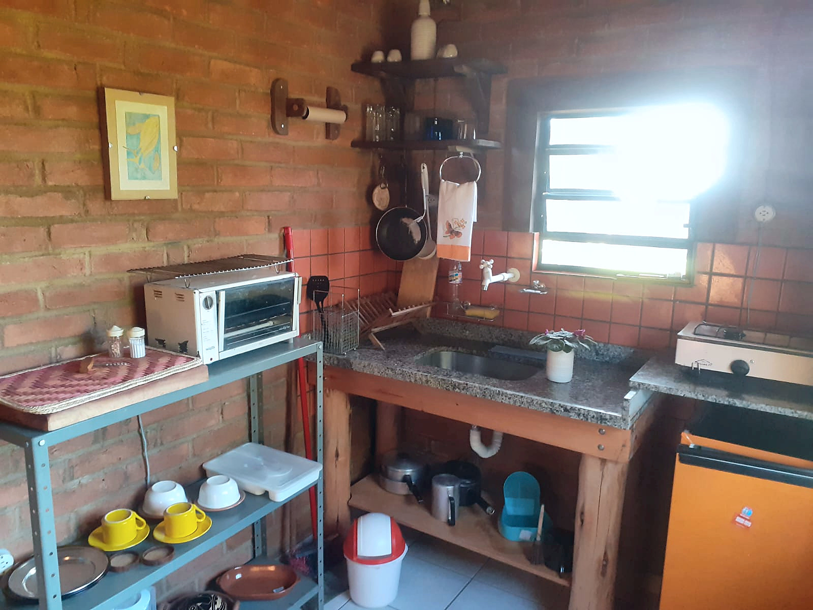 Cozinha de tijolos aparentes e pia na Estalagem Pintassilgos